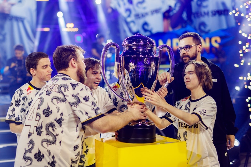 киберспортсмен держит золотой кубок на фоне толпы